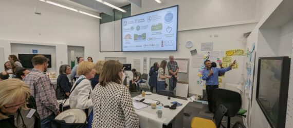 People stood around a whiteboard engaged in a discussion