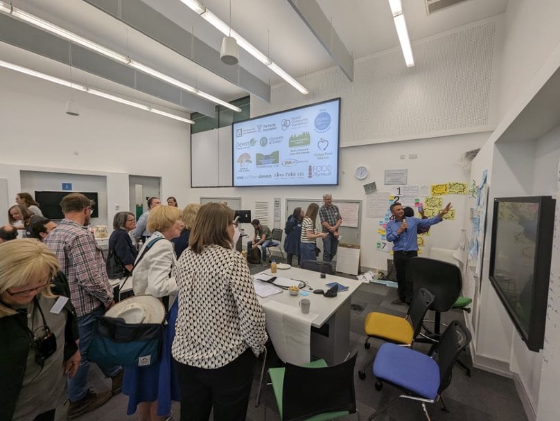 People stood around a whiteboard engaged in a discussion