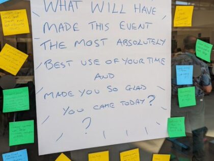 Post it notes with writing on surrounding a poster reading 'what will have made this event the most absolutely best use of your time and made you so glad you came?'