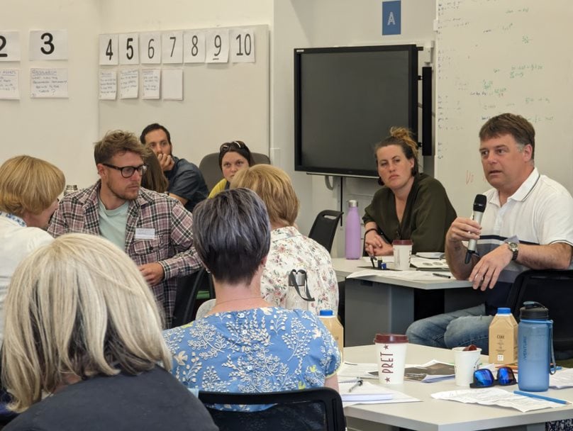 Someone speaking into a microphone while others listen