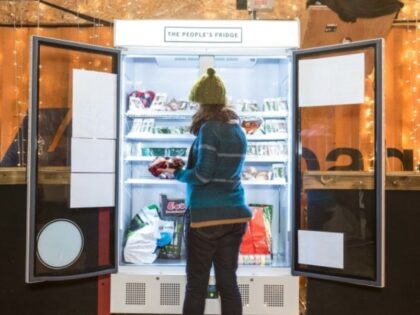 open doored community fridge with person picking items